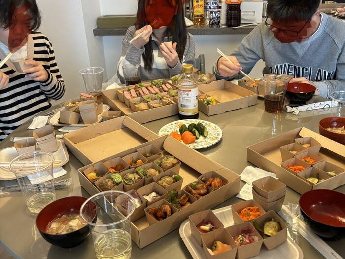 中学生と小学生が夢中で食べています。大人はそれん見ながら食べています。